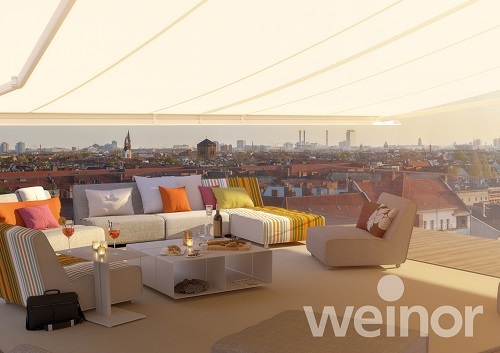 Moderne Dachterrasse mit stilvollen Loungemöbeln und Markise mit Stadtblick bei Sonnenuntergang.
