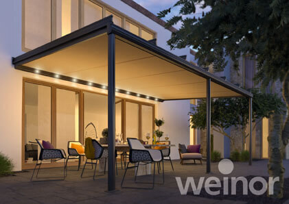 Moderne Terrassenüberdachung mit LED-Beleuchtung und Gartenmöbeln bei Dämmerung.